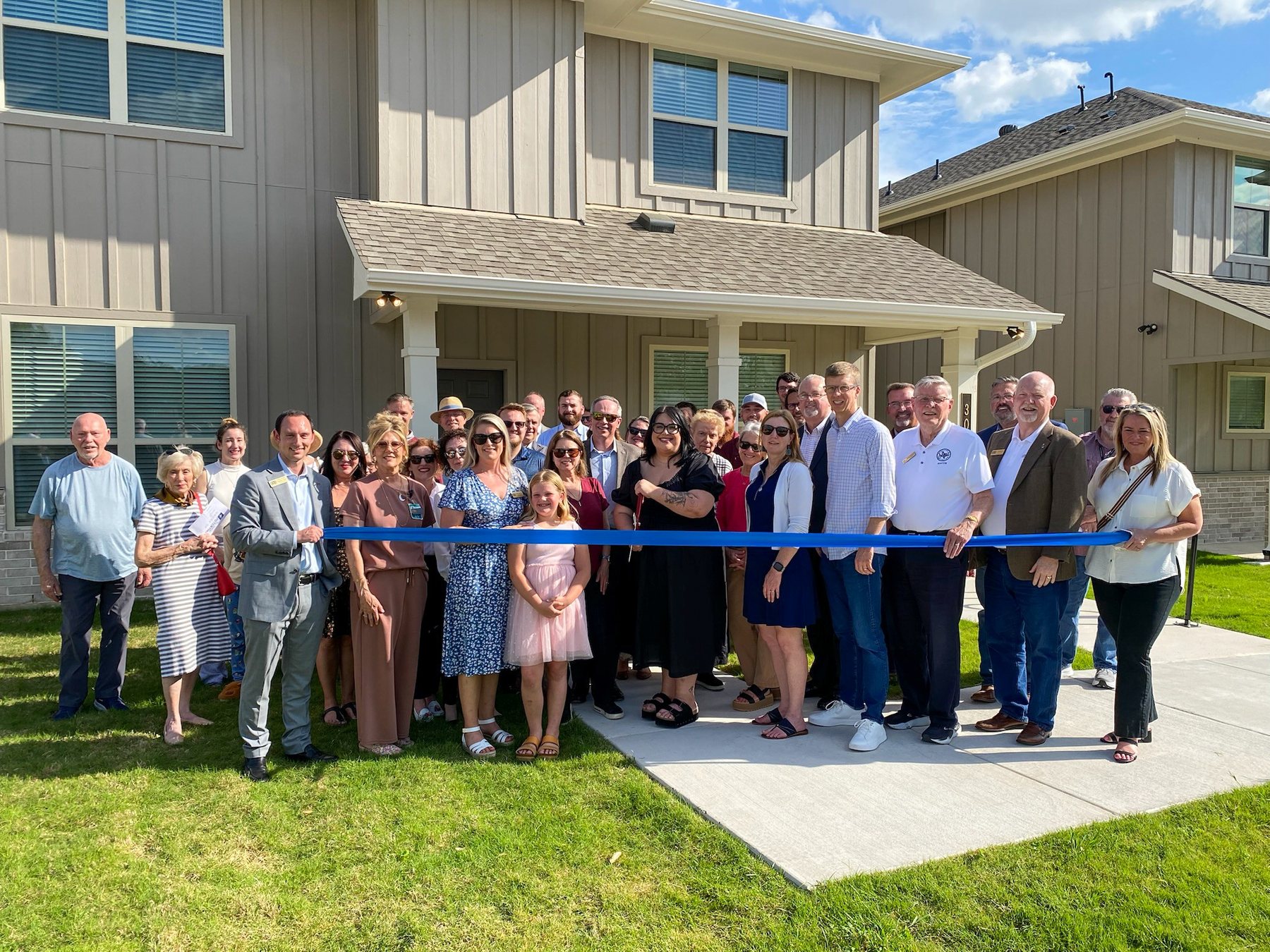 Community members gathered for a ribbon cutting outside Unlimited Potential housing