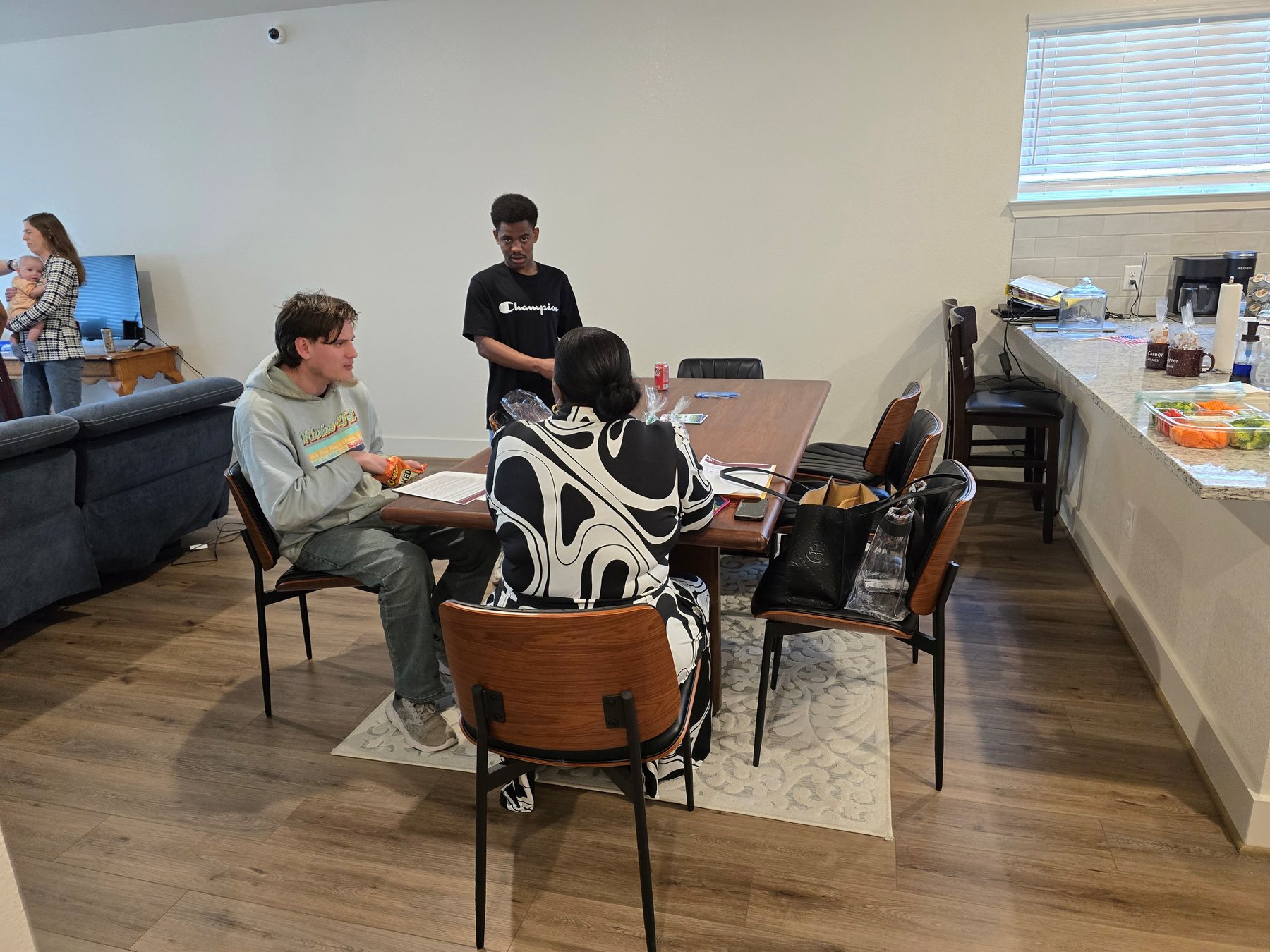 Young adults and supporters gathered around a table in a home setting